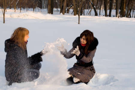 Two female friends walking in park in winterの写真素材