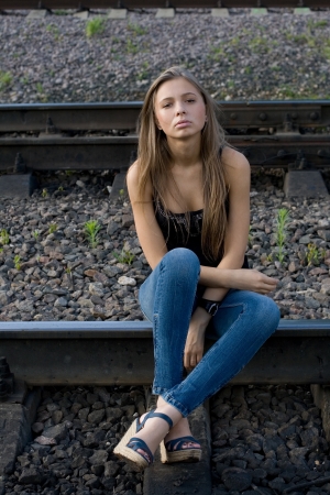 Girl sitting on railsの写真素材