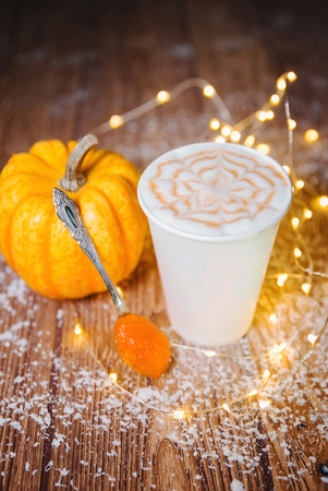 Cup of coffee with heart shape and pine cone with acorn and pumpkin on wooden backgroundの写真素材