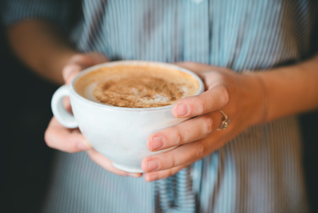girl holding  cup of coffee close-upの写真素材