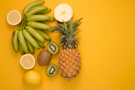 Fruits cut on a bright yellow background with a place for writingの写真素材