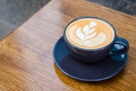 Cappuccino in a dark blue cup on a wooden table