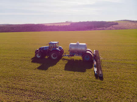 The introduction liquid mineral fertilizers into soil with tractor winter wheatの写真素材
