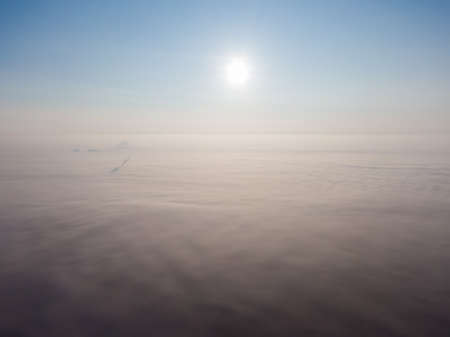 Aerial view of the city in the fog in the haze of clouds. Emissions into the atmosphere from industrial pipes.の写真素材