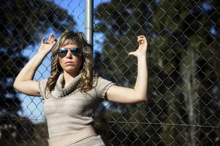 young woman posing in a sensual resting on a fenceの写真素材