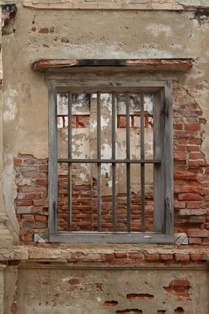 rendered concrete wall with exposed red brick and wooden jail cell like window. Abstract texture background with copy space, Exposed, Fenced In or Closed Off concept in vertical viewの写真素材