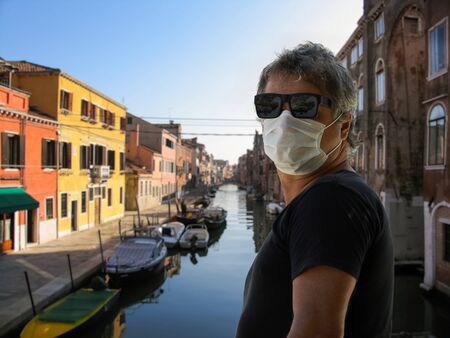 male wearing face mask in a empty Venice street after the coronavirus Italy lockdown, deserted Venice street amid coronavirus fears, taken on dusk in Venice Italyの写真素材