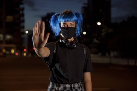 stop coronavirus social distancing concept, young female with blue hair wearing a stylish protective...
