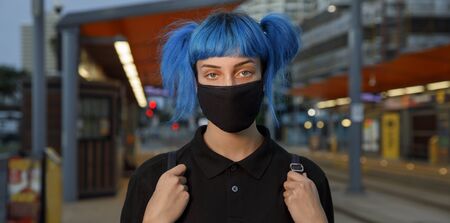 coronavirus fashionable medical face mask worn by young female student with blue anime style hair,...