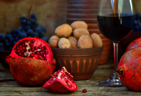pomegranate, walnuts and glass of wine on a wooden backgroundの写真素材