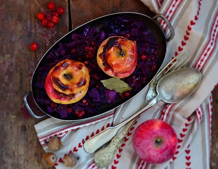 stewed red cabbage with the stuffed apples in a metal vintage bowl on a wooden backgroundの写真素材