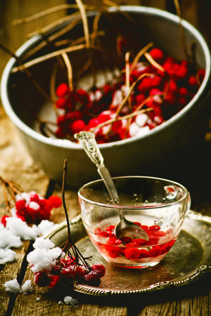 fresh berries of a guelder-rose in a glass cup on a wooden table. style rustic.  the image is tintedの写真素材
