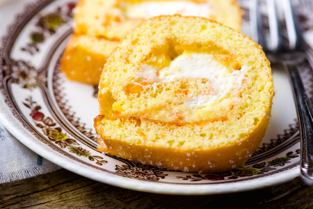swiss roll with whipped cream and orange cream. style rustic. selective focus