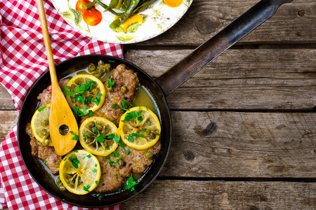 picatta from veal with a lemon in a vintage frying pan. top view. selective focusの写真素材
