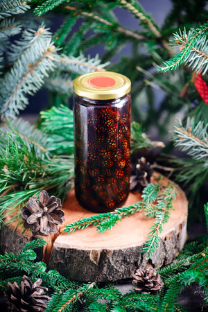Jam from young pine cones in syrup on a background with pine branches.style rustic.selective focus