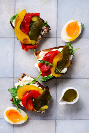 Bruschetta with cream cheese, baked bell peppers, arugula and soft-boiled egg..top view.selective...