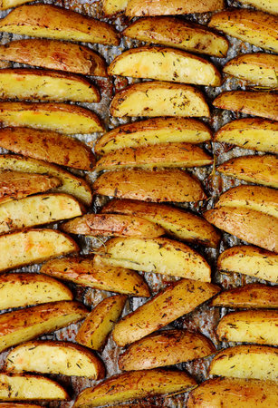 Roasted potato wedges with olive oil and herbs on a baking sheet .top veiw.selective focusの写真素材