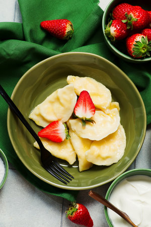 Dumplings with cottage cheese and fresh strawberries and sour cream and butter. Ukrainian cuisine.top veiw. selective focusの写真素材