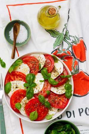 Traditional Italian caprese salad with tomatoes, mozzarella and basil on a white plate. top veiw.selective focusの写真素材