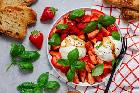 Salad with strawberries, burrata, basil, honey and balsamic on a white plate. top veiw.selective focusの写真素材