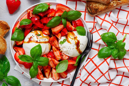 Salad with strawberries, burrata, basil, honey and balsamic on a white plate. top veiw.selective focusの写真素材