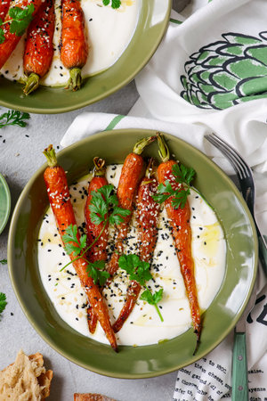 Baked baby carrots in honey glaze on whipped feta in a ceramic bowl. selective focus.top veiwの写真素材