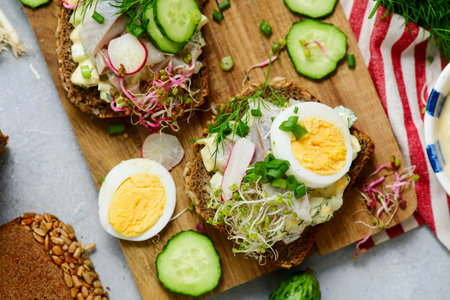Danish Open-Faced Sandwich with herring on slices of rye bread with boiled egg, fresh cucumber,...