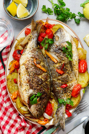 Baked Dorado with Vegetables, Potatoes, Sweet Peppers, Cherry Tomatoes, Onions and Garlic.top veiw.selective focusの写真素材