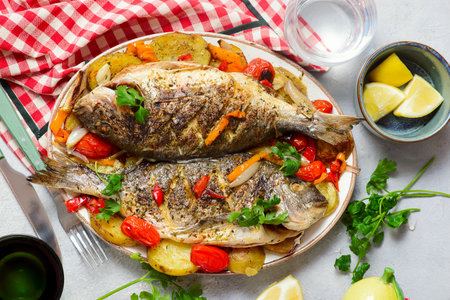 Baked Dorado with Vegetables, Potatoes, Sweet Peppers, Cherry Tomatoes, Onions and Garlic.top veiw.selective focusの写真素材
