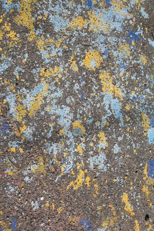 Blue and yellow paint splattered randomly on asphaltの写真素材