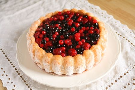 Whole sponge cake topped with raspberry, blueberry, and currants on a white dish-Angled Viewの写真素材