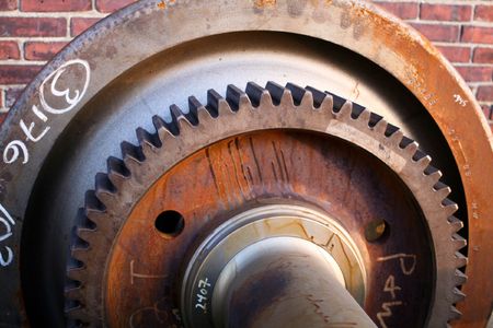 A rusty old gear wheel centered in front of a brick wallの写真素材