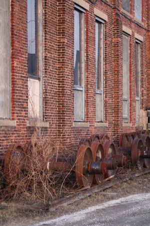 a row of rusty train axles beside a brick buildingの写真素材