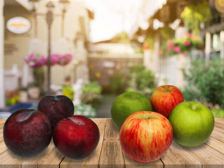 4 Apples, 3 Plum at wooden table in backgroundの写真素材
