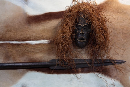 An African mask with a spear on an antelope coat.の写真素材