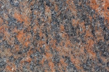 Macro photo of the surface of a gneiss rock containing with red minerals.
