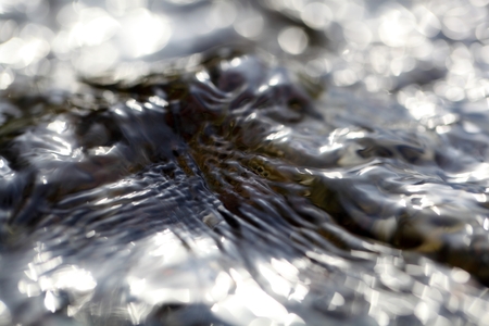 Macro photo of the surface of water in a creek with light reflections.の写真素材