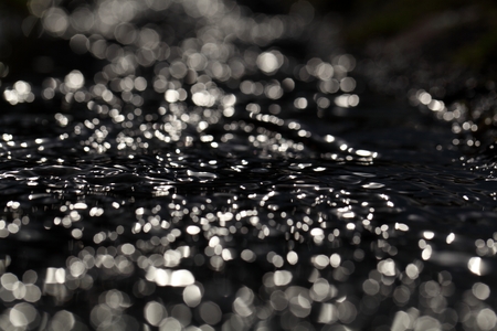 Macro photo of the surface of water in a creek with light reflections.