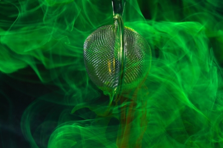 A tea ball with fluorescein in water.  Fluorescein is a green, fluorescent coloring agent for water.の写真素材