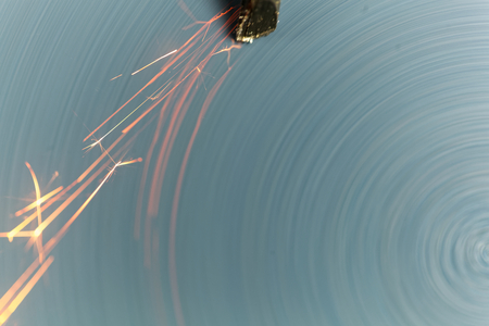 Macro photo of a steel tool on a grinder with sparks.