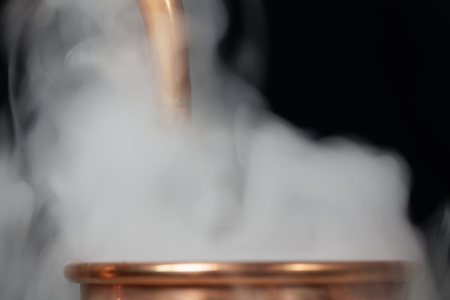 A copper pipe of a distillery with steam.