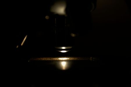 Macro photo of a microscope objective with a slide and a dark background.の写真素材