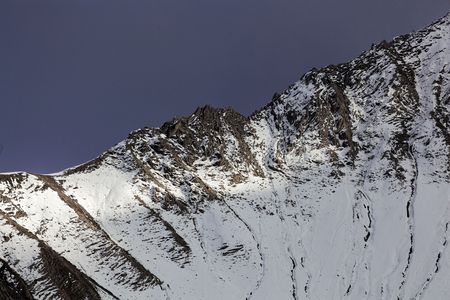 Mountains in the Western Rhaetian Alps in Switzerland, with clouds and sun.