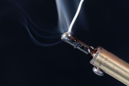Macro photo of melting tin on the tip of a soldering iron