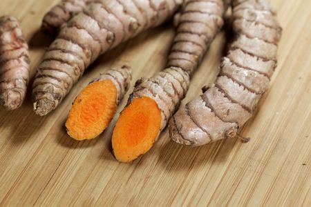 Several curcuma roots on a wooden background.