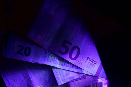 Banknotes in the beam of an UV flash light.の写真素材