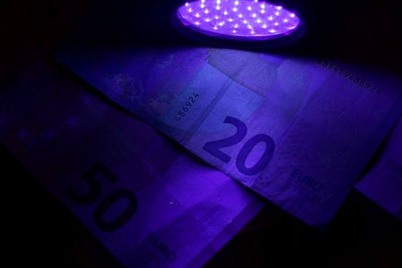 Banknotes in the beam of an UV flash light.の写真素材