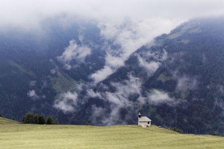 Cloudy alpine landscape with a small chapel in Austria.の写真素材