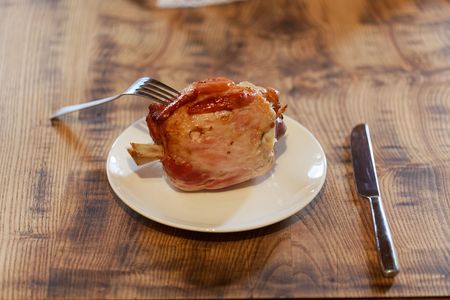 A Eisbein (pickled ham hock) on a white plate and wooden background.の写真素材