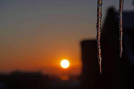 Sunset winter scene with two icicles in a city.